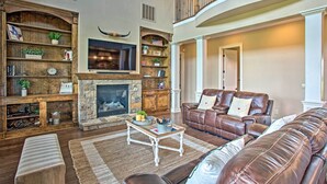 A spacious living room with a fireplace, leather sofas, and a wooden bookshelf. - Home w/ Game Room & Fireplace: 14 Mi to Mckinney! (Blue Ridge)