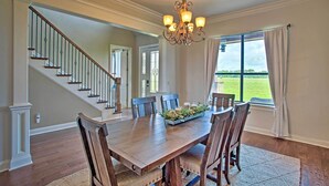 A dining room with a wooden table, chairs, a chandelier, and a view of a green field through a window. - Home w/ Game Room & Fireplace: 14 Mi to Mckinney! (Blue Ridge)