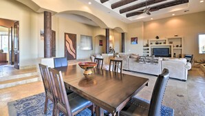 Uma sala de estar ampla com uma mesa de jantar de madeira, assentos confortáveis, lareira e televisão.