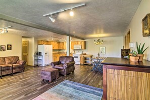 A spacious living area with a wooden floor, leather furniture, a kitchen with wooden cabinets, and a dining area.