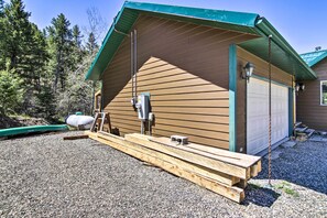 Eine Holzhütte mit grüner Dachdeckung, einer Garage und einer Zuwegung mit Kies.
