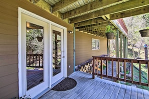 A wooden deck with a covered porch, a door, and hanging planters.