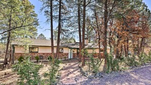 A two-story house with a brick exterior and a green door, surrounded by tall trees and a gravel driveway. - 'lakeside Traditions' Arizona Home w/ Game Room! (Lakeside)