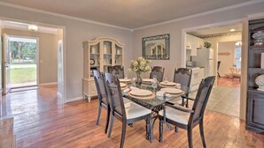 A dining room with a glass table, dark chairs, and a white cabinet with shelves. - Hilton Head Waterfront Golf Getaway: Pet Friendly! (Hilton Head Island)