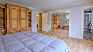 A bedroom with a large bed, wooden wardrobe, and a sliding glass door leading to a bathroom. - Hilton Head Waterfront Golf Getaway: Pet Friendly! (Hilton Head Island)