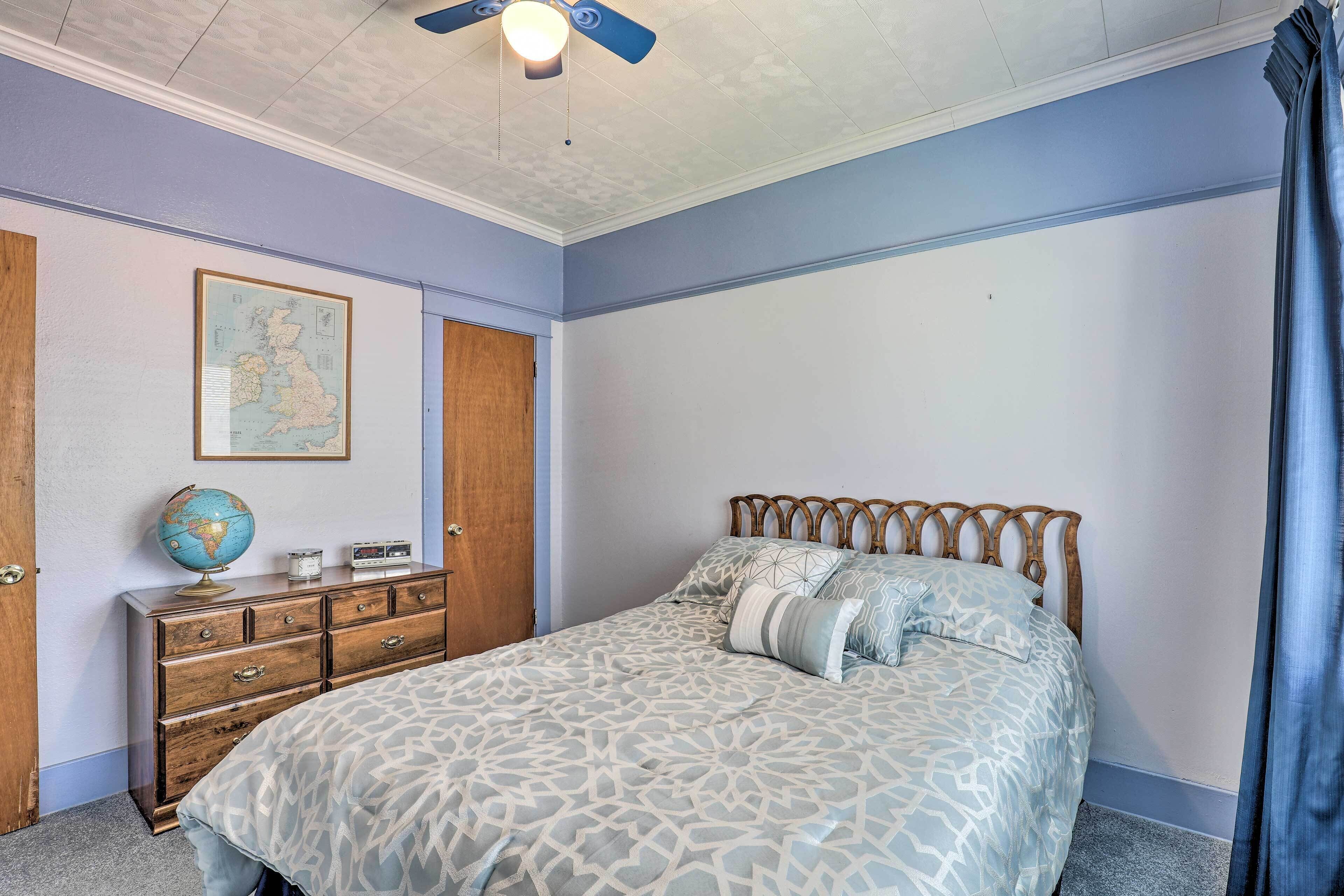 A bedroom with a bed, dresser, globe, and a map on the wall.