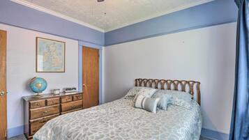 A bedroom with a bed, dresser, globe, and a map on the wall.