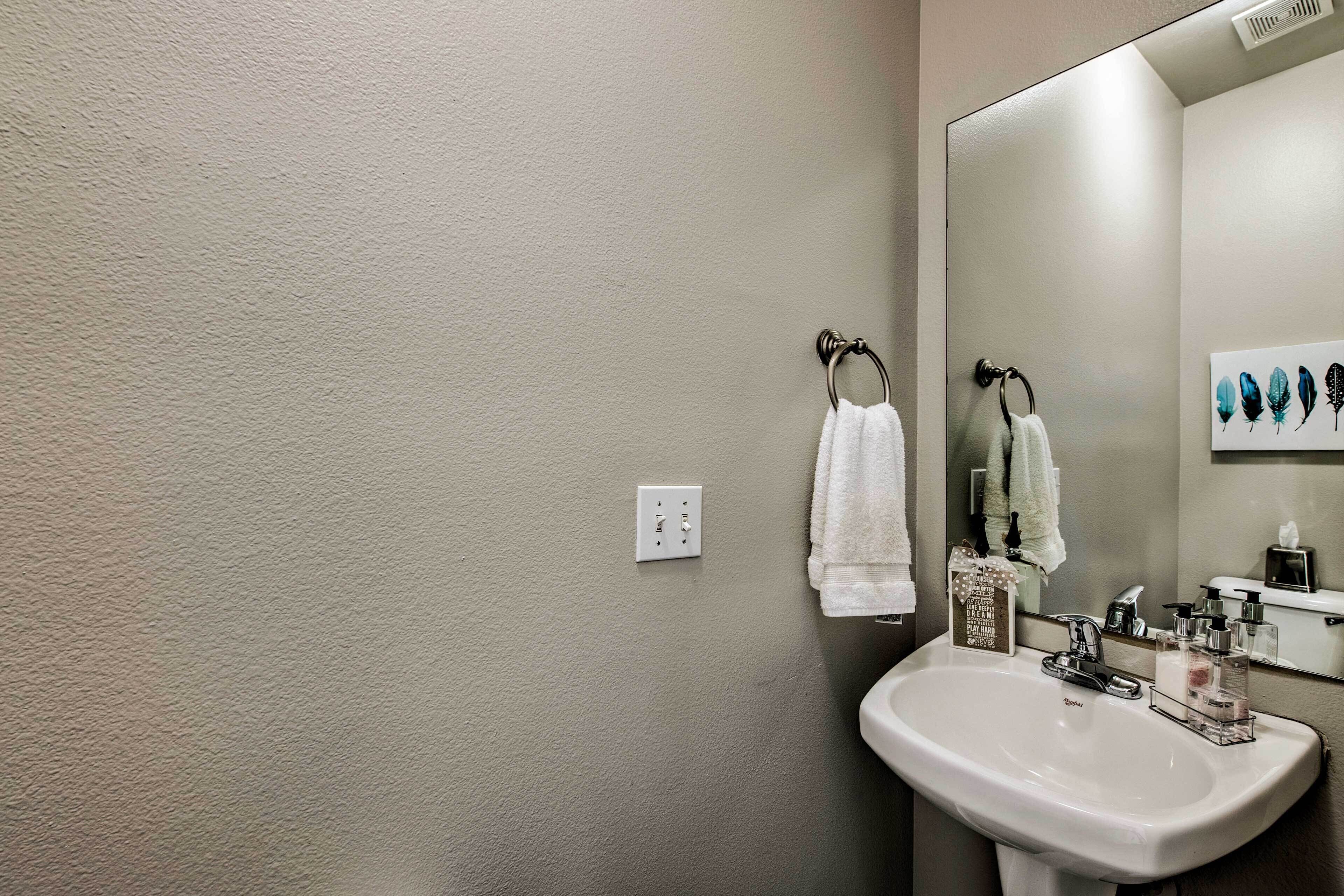 A bathroom with a white sink, a mirror, and two towels hanging on towel rings.