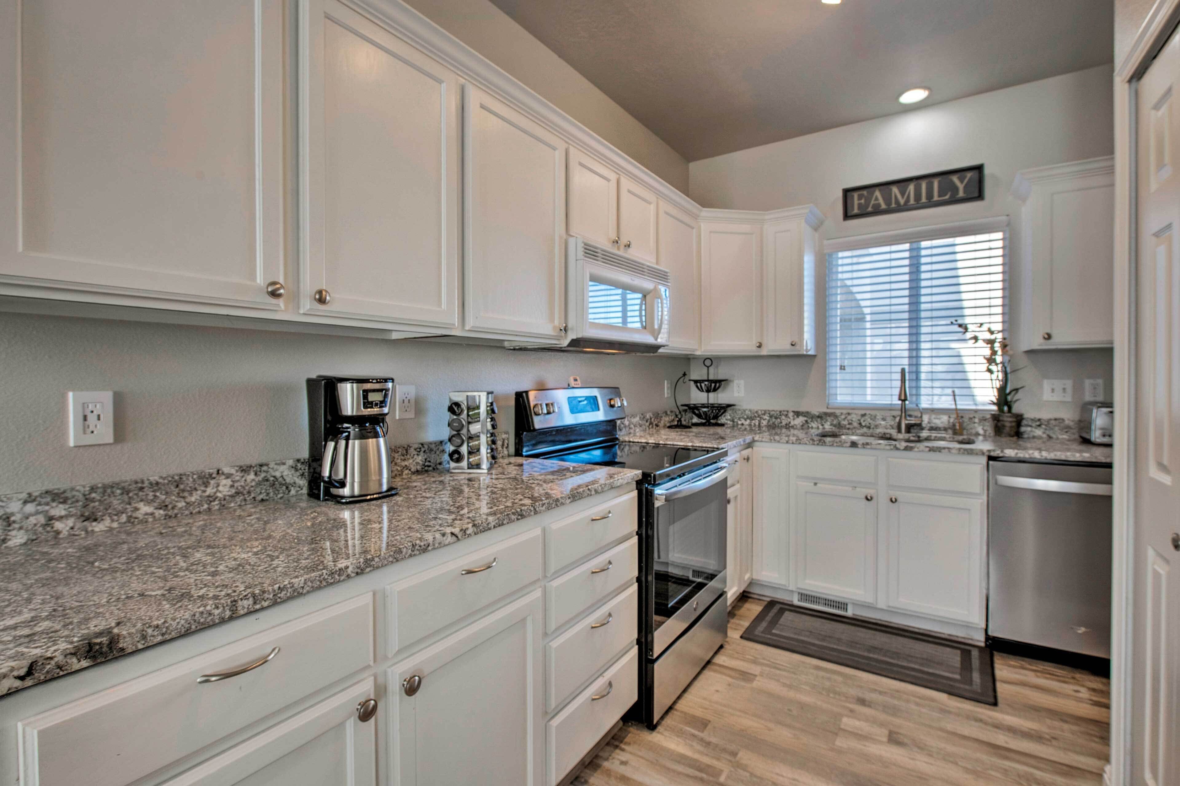A kitchen with white cabinets, a granite countertop, a stainless steel oven, and a coffee maker.