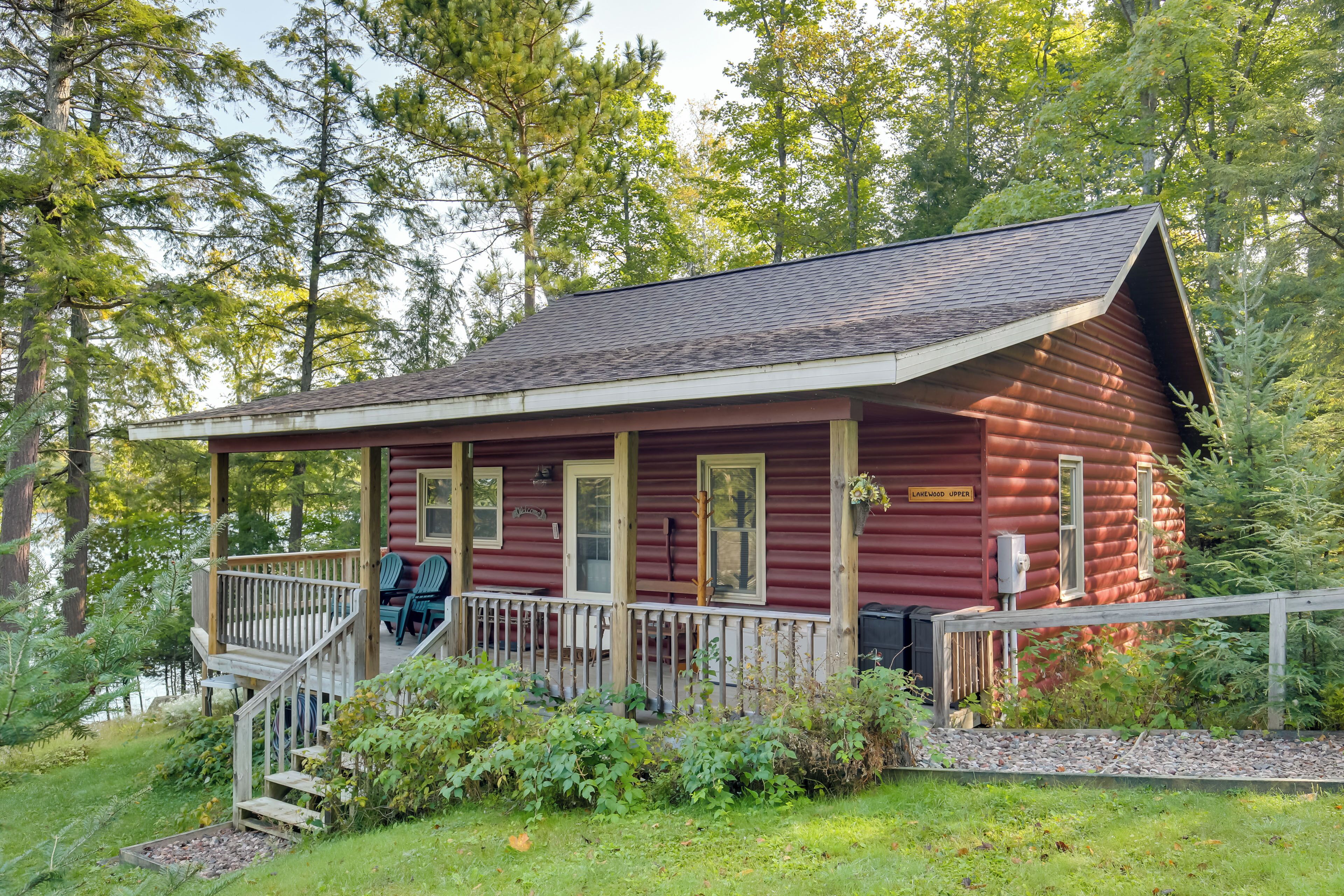 A log cabin with a porch, two windows, and a 'Welcome' sign.