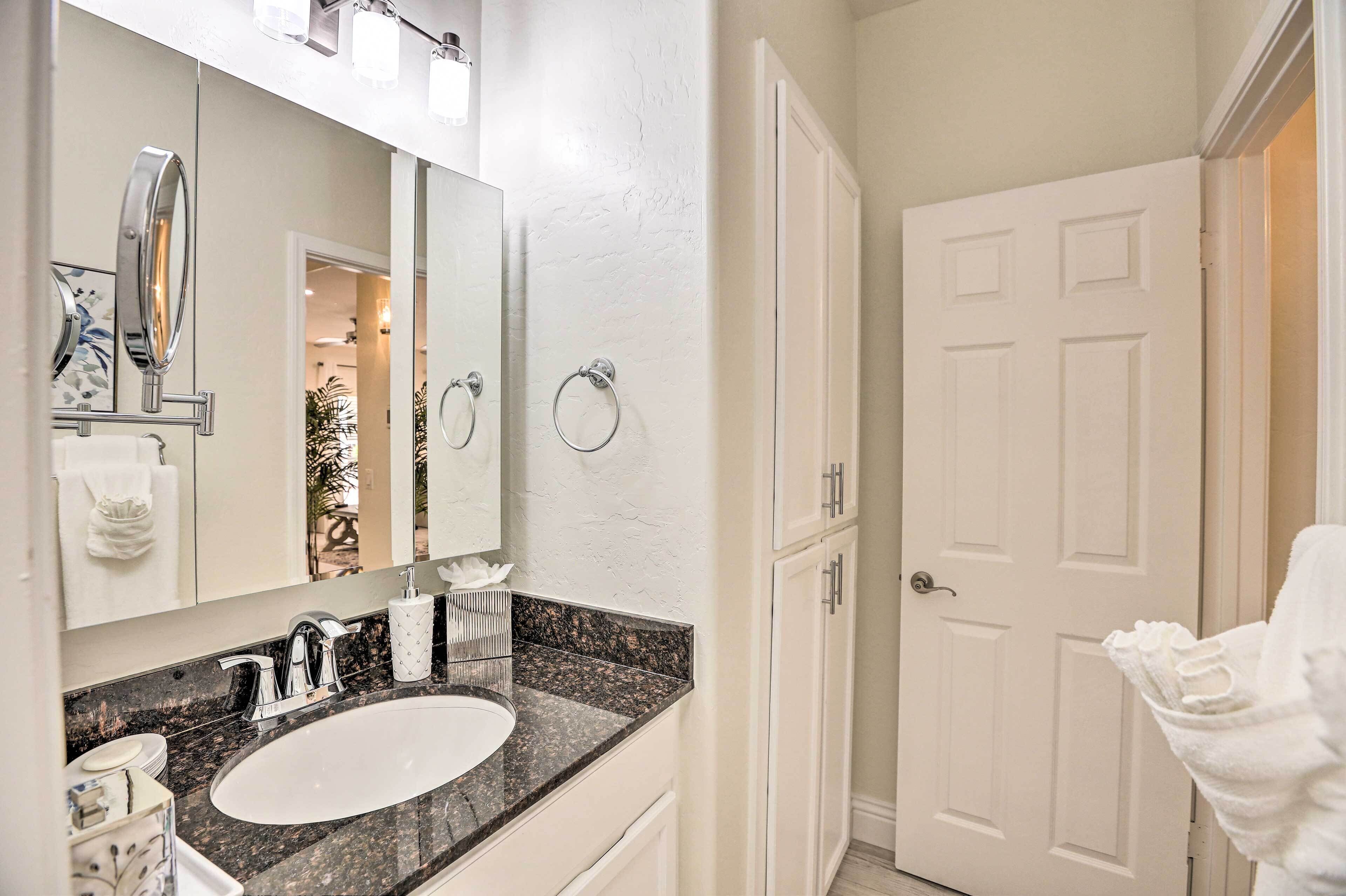 A bathroom with a white sink, a large mirror, and a door leading to another room.
