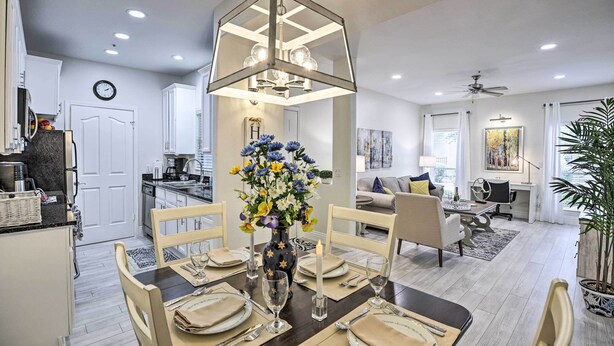 A modern kitchen with white cabinets, a dining area with a dark wooden table set for four, and a living room with a sofa and coffee table. - Bright Scottsdale Condo w/ Patio: 8 Mi to Old Town (Scottsdale)