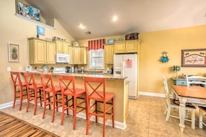 A kitchen with yellow cabinets, a white refrigerator, and a red island with bar stools.