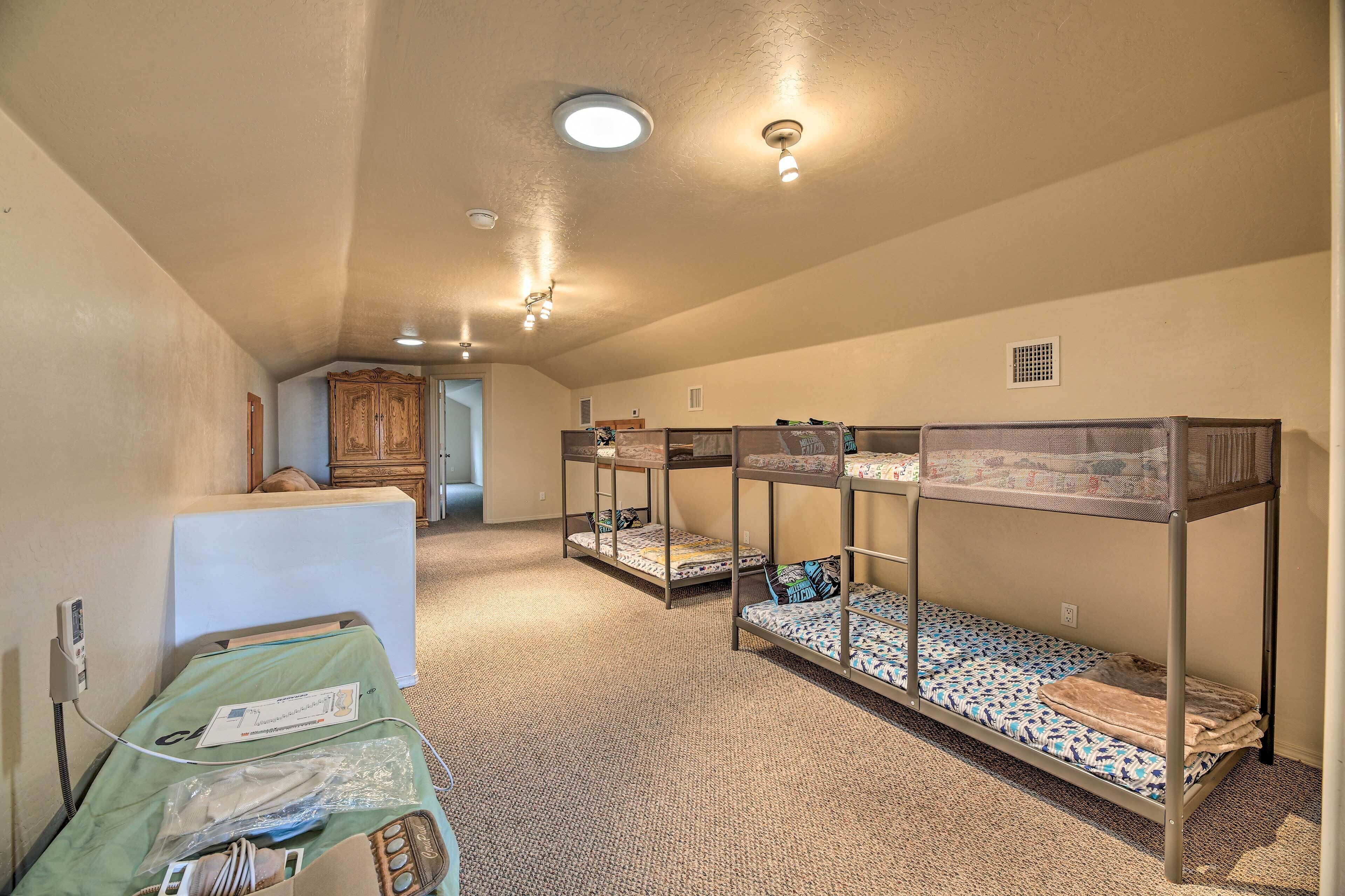 A room with bunk beds, a green bed with medical equipment, and a small kitchenette.