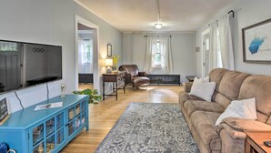 A living room with a large flat-screen TV, a blue entertainment unit, a brown sofa, and a patterned rug. - Enchanting Family House w/ Balcony < 3 Mi to Wvu! (Morgantown)