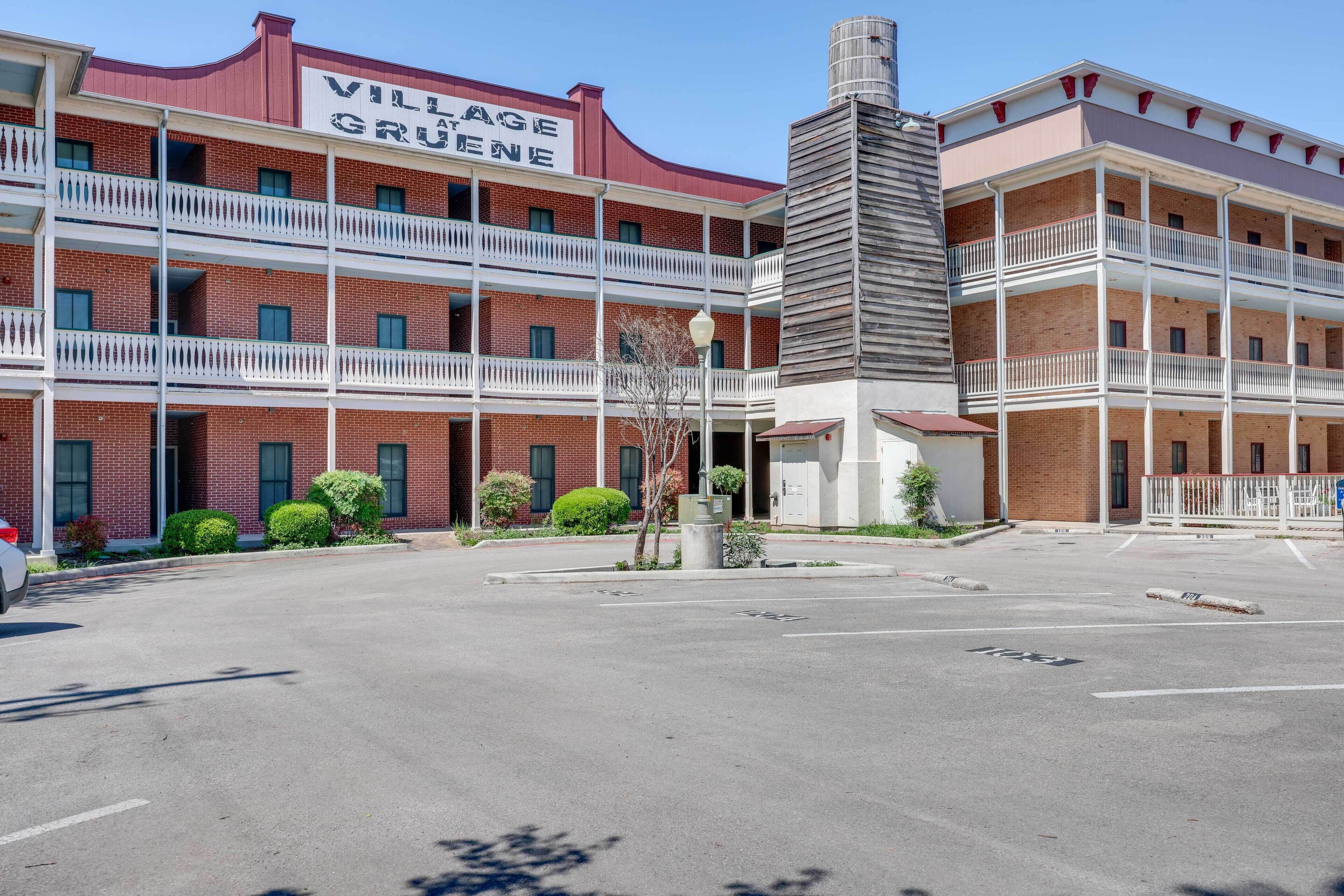 Un hôtel à plusieurs étages, reconnaissable à son enseigne bien visible indiquant « Village Grüne ». Il se distingue par sa façade en briques, ses nombreux balcons et un parking situé à l’avant.
