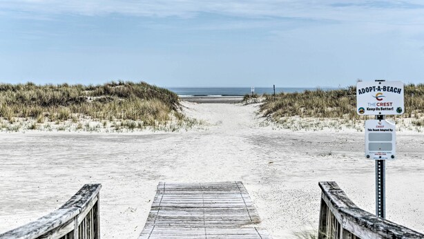 A beach path leading to the ocean with a sign reading "Adopt-a-Beach The Crest Keep Us Better!". - Condo w/ Pool Access on Wildwood Crest Beach! (Wildwood Crest)