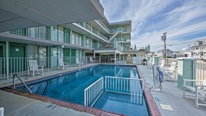 A swimming pool with a 3FT and 1FT depth marking, surrounded by a multi-story building with balconies and a clear sky. - Condo w/ Pool Access on Wildwood Crest Beach! (Wildwood Crest)