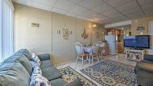 A living room with a sofa, dining table, and TV. - Condo w/ Pool Access on Wildwood Crest Beach! (Wildwood Crest)
