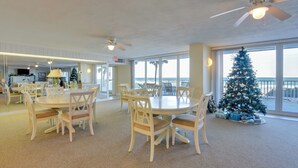 Un vaste espace dédié à la salle à manger, avec des tables et des chaises rondes, un ventilateur de plafond et une grande fenêtre donnant sur la plage.