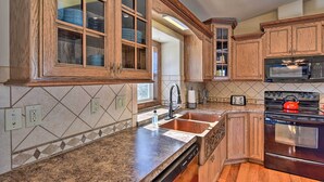 A kitchen with wooden cabinets, granite countertops, a stainless steel sink, a red kettle, and a built-in microwave. - 2 Mi to Hot Springs: Nathrop Gem w/ Fire Pit (Nathrop)