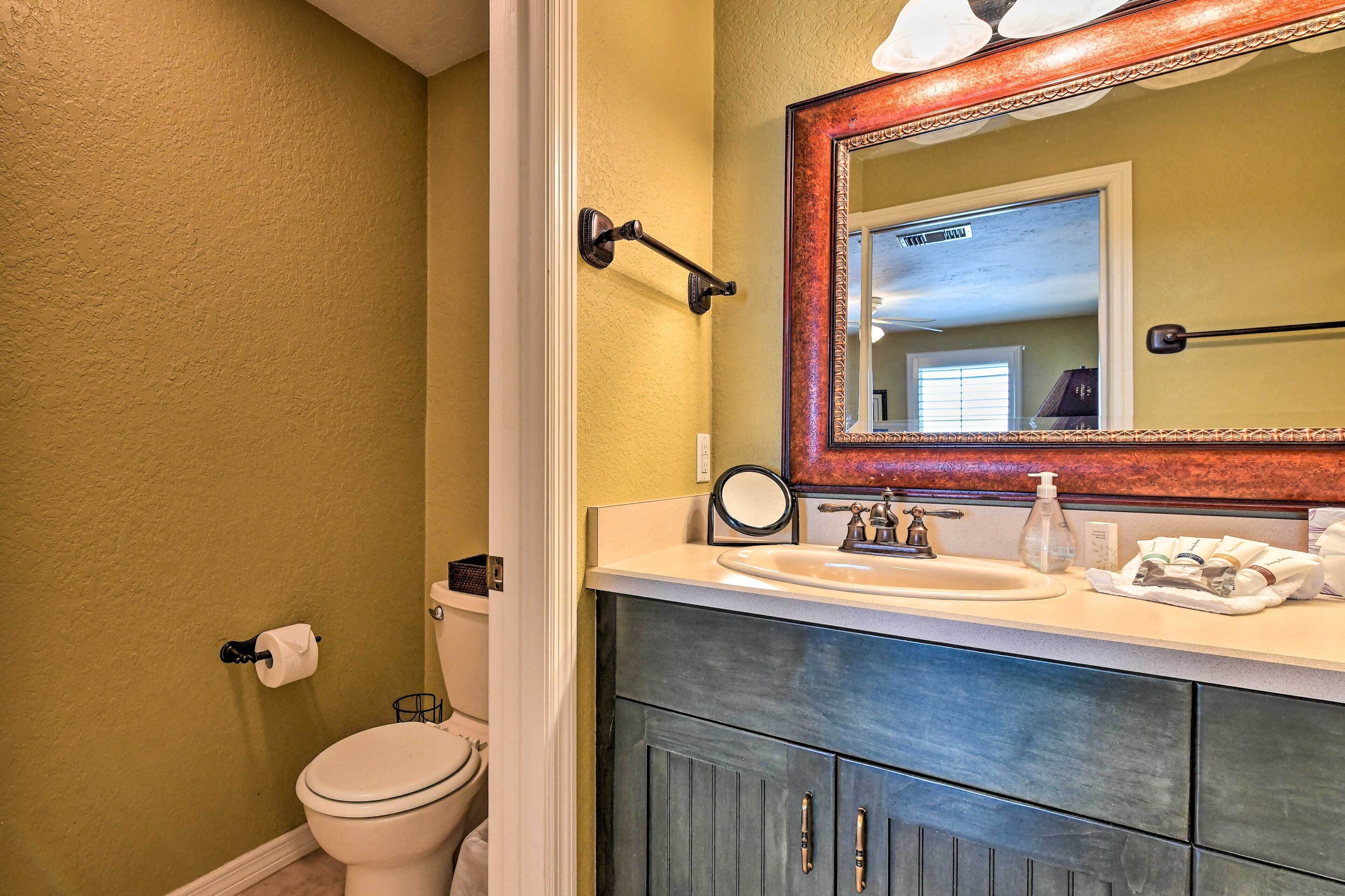 A bathroom with a toilet, sink, and mirror.