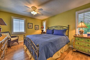 Classic bedroom with a bed, dresser, wicker chair, and framed pictures.