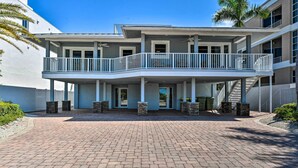 A multi-story building with a covered walkway, stone pillars, and a palm tree. - Bright Coastal Condo: Walk to Lido Key Beach! (Sarasota)