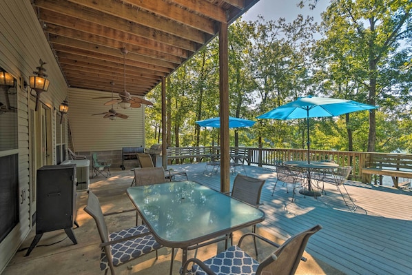 Une terrasse extérieure avec une table et des chaises, un ventilateur de plafond et un barbecue.