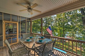 Eine überdachte Terrasse im Freien mit einem für vier Personen gedeckten Tisch, umgeben von Korbstühlen und einer amerikanischen Flagge.