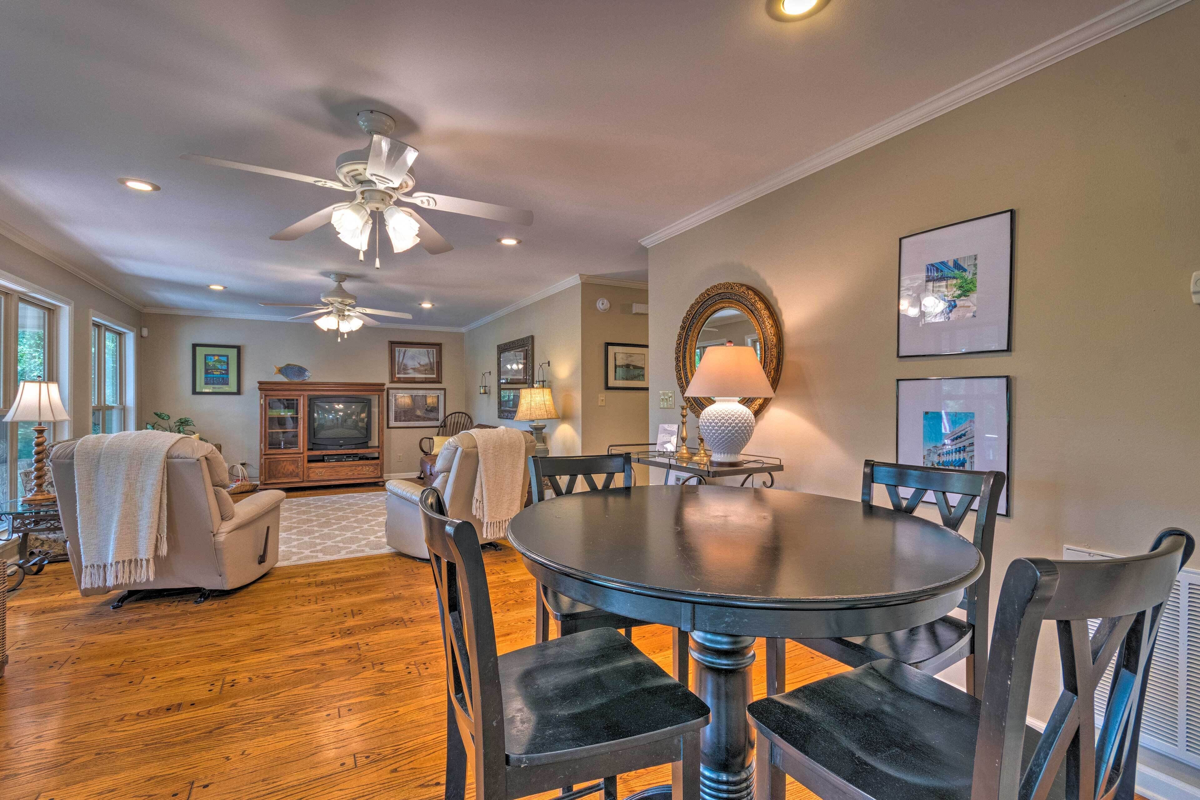 A dining area with a round table, dark chairs, and ceiling fans.