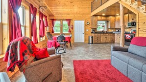 A cozy cabin interior with a dining area, kitchen, and a staircase leading to an upper level. - Cozy Haven of Rest Home w/ Amish Country Views! (Shipshewana)