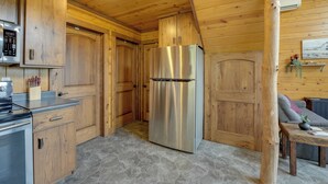 A wooden interior with a stainless steel refrigerator, wooden cabinets, and a stone-tiled floor. - Cozy Haven of Rest Home w/ Amish Country Views! (Shipshewana)