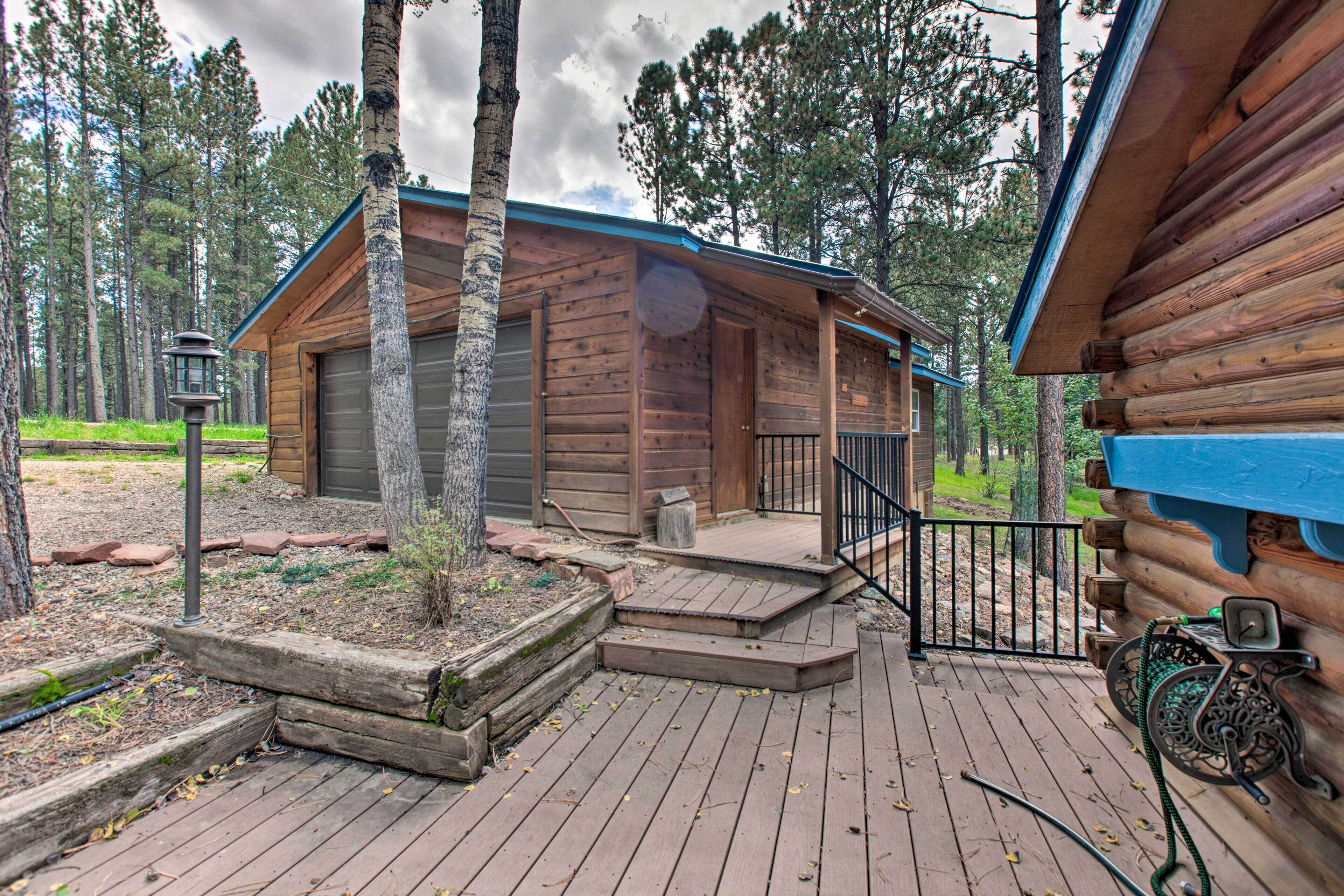 A log cabin with a porch, a bicycle, and a small garden area.