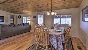 A dining area with a wooden ceiling, a dining table set with plates, glasses, and a chandelier. - Rustic Bullhead City Retreat w/ Porch & Views (Bullhead City)