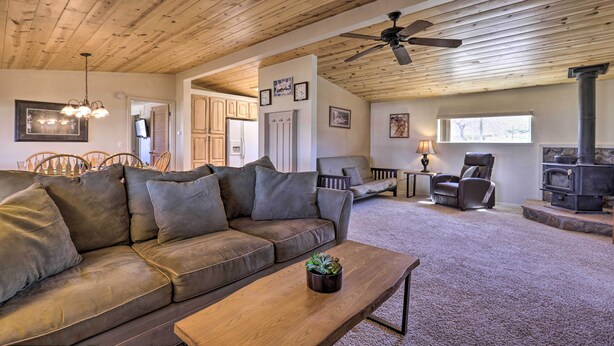 A cozy living room with a wooden ceiling, a brown leather sofa, a wooden coffee table, and a fireplace. - Rustic Bullhead City Retreat w/ Porch & Views (Bullhead City)