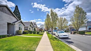 A suburban street with single-family homes, a sidewalk, and parked cars.