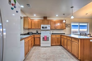 A kitchen with wooden cabinets, a white stove, a microwave, and a dishwasher.