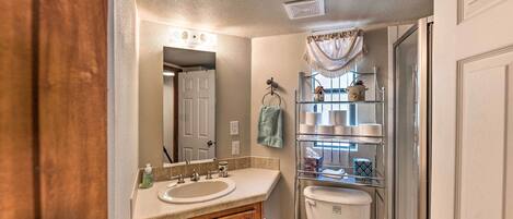 A bathroom with a wooden vanity, a white sink, a mirror, a towel rack, and a shower enclosure.