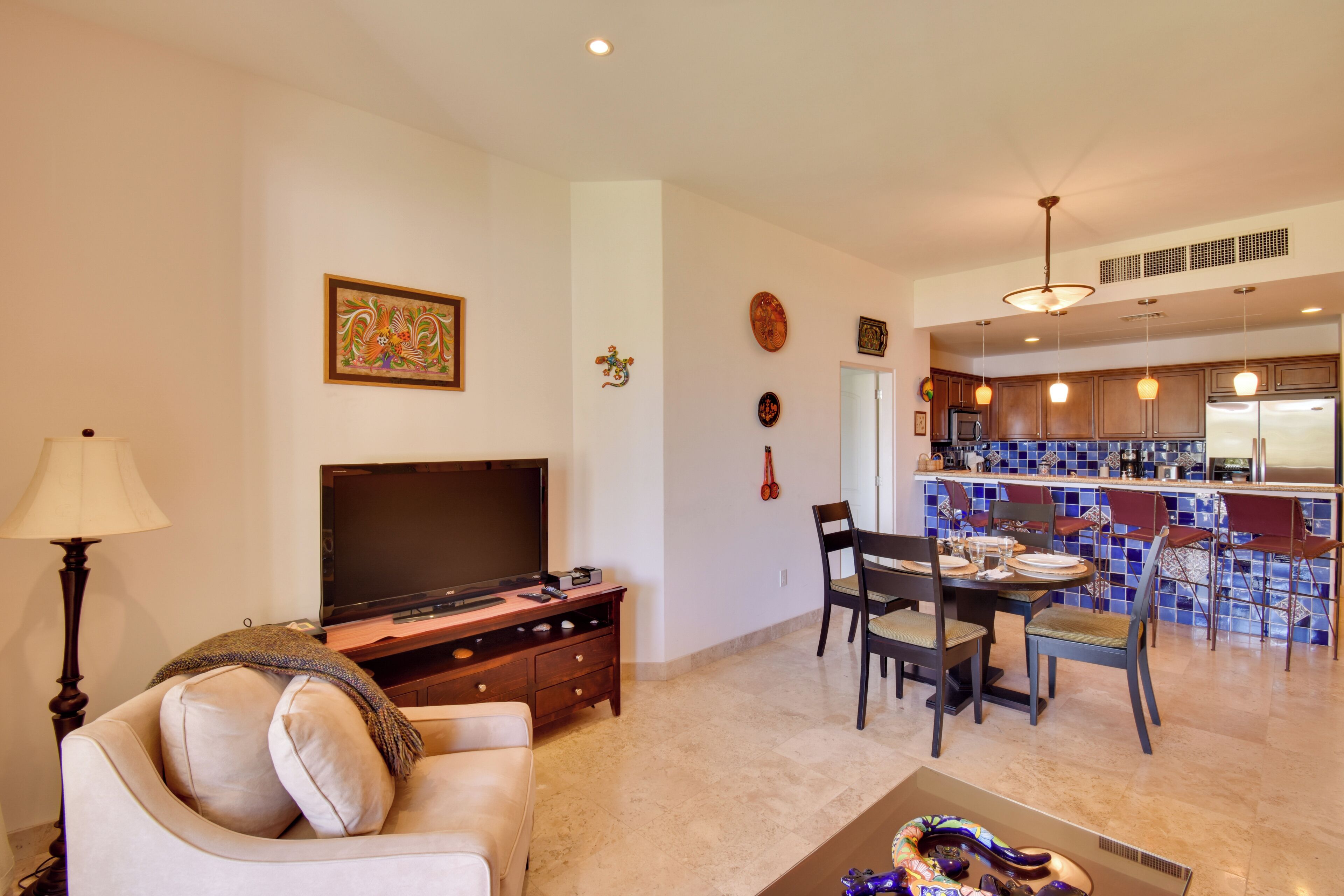 A living room with a TV, sofa, and dining area with chairs and a table.