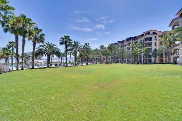 A hotel courtyard with palm trees, a pool, and a building with balconies. - Gulf-view Condo: Private Patio, Pool & Golf! (La Paz)