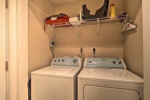 Une buanderie équipée de deux machines à laver à chargement frontal et d’une étagère au-dessus pour ranger les produits de nettoyage.