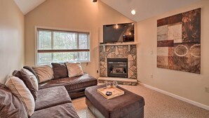A living room with a stone fireplace, a large TV, and a ceiling fan. - 6 Mi to Skiing: Family Poconos Home w Decks! (Albrightsville)