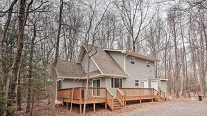 A two-story house with a wooden deck and a covered porch, surrounded by a wooded area. - 6 Mi to Skiing: Family Poconos Home w Decks! (Albrightsville)
