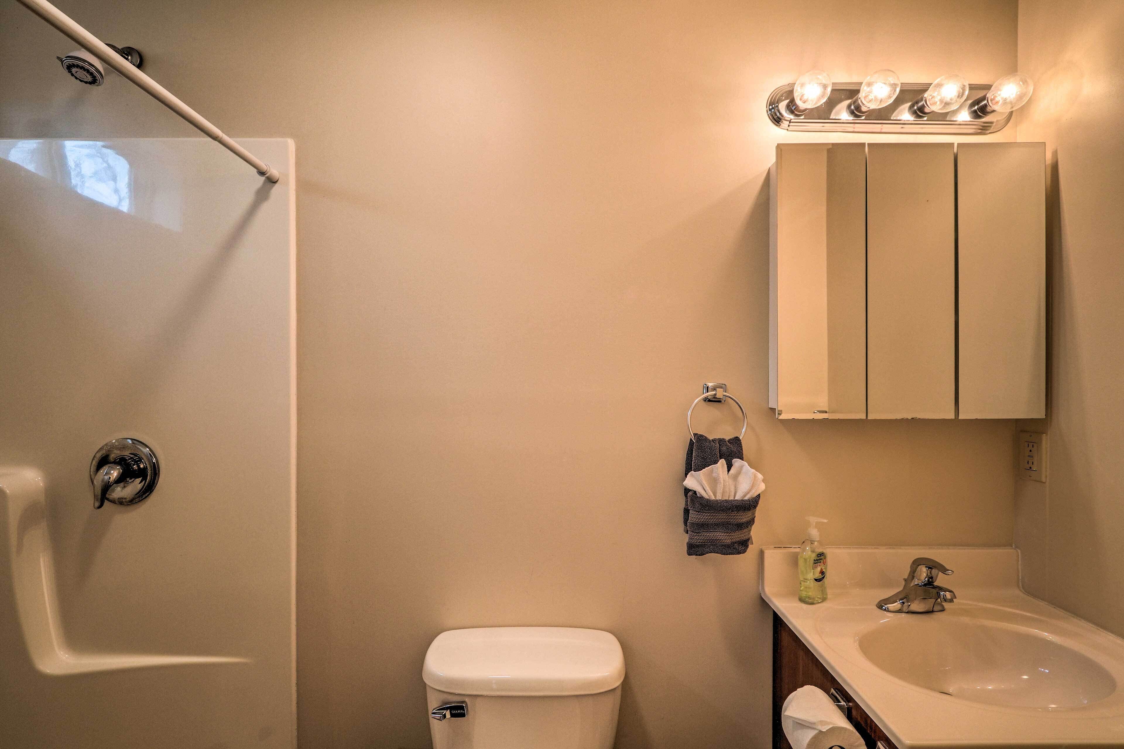 A bathroom with a shower, toilet, sink, and vanity cabinet.