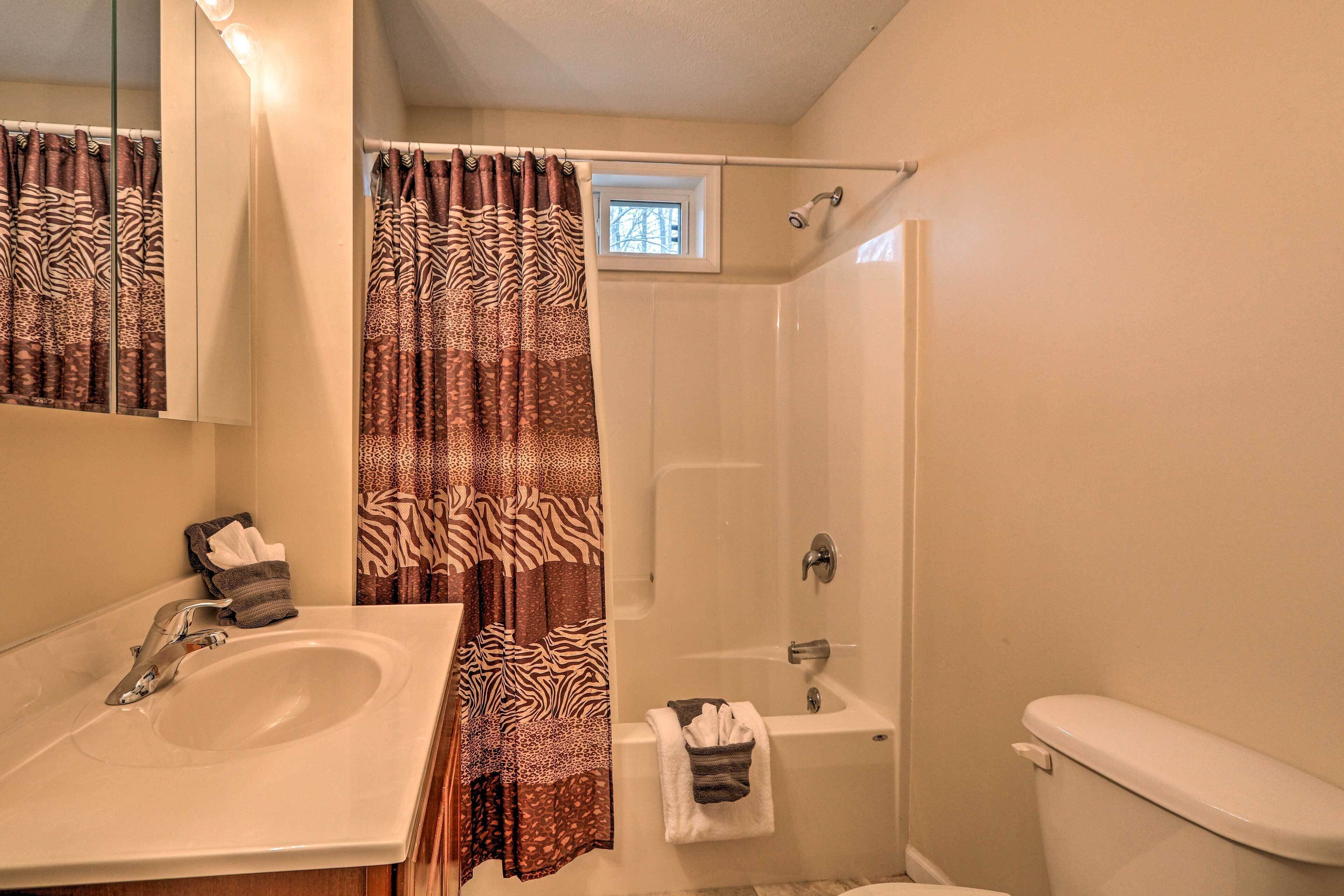 Une salle de bain équipée d’un lavabo, d’un miroir, d’une douche et de toilettes.