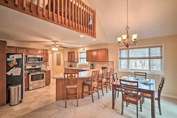 A spacious kitchen with wooden cabinets, a central island, and a dining area with wooden chairs and a table.