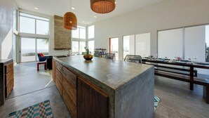 A spacious kitchen with a large island, wooden cabinets, and a view of the outdoors.