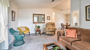 A living room with a brown sofa, a teal chair, a yellow armchair, a large mirror, and a small table with a lamp and a plant. - Fishing Paradise w/ Deck On Suwannee River (Branford)