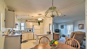 A modern kitchen with white cabinets, a dining area with a wooden table and chairs, and a ceiling fan. - Fishing Paradise w/ Deck On Suwannee River (Branford)